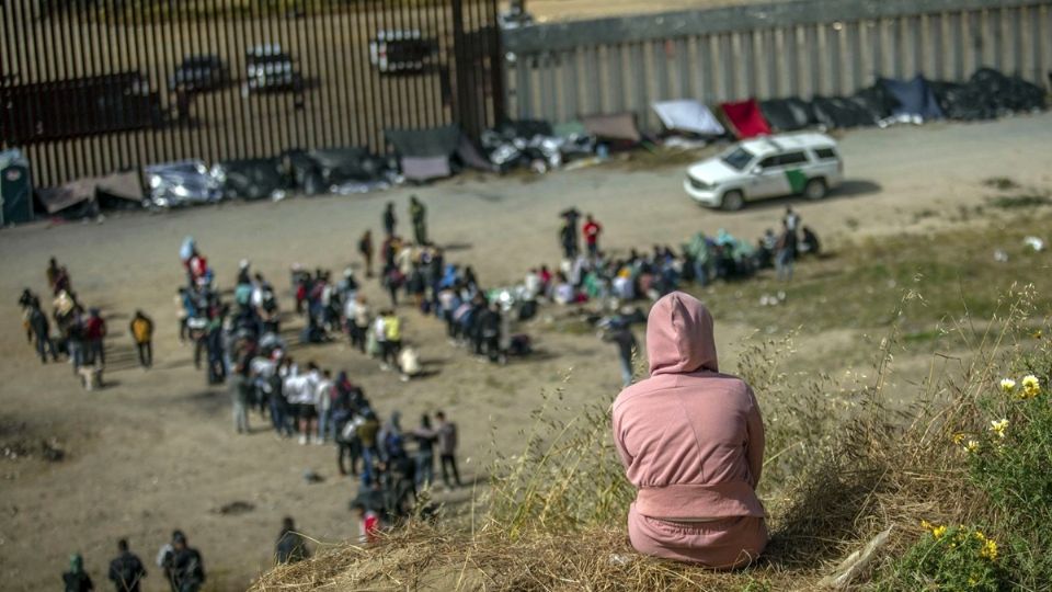 Cientos de migrantes se encuentran entre los dos muros fronterizos que dividen a Tijuana de Estados Unidos.