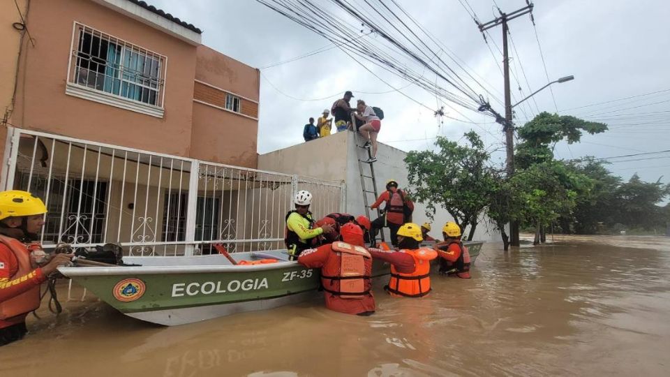 Elementos de Protección Civil auxilian a personas que quedaron atrapadas en viviendas por las inundaciones.