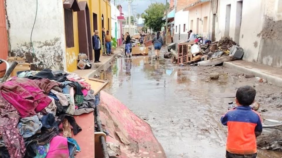 Ocampenses sacan sus pertenecientes a la calle mientras un niño al fondo de la calle observa el desastre  que causó el agua en su paso