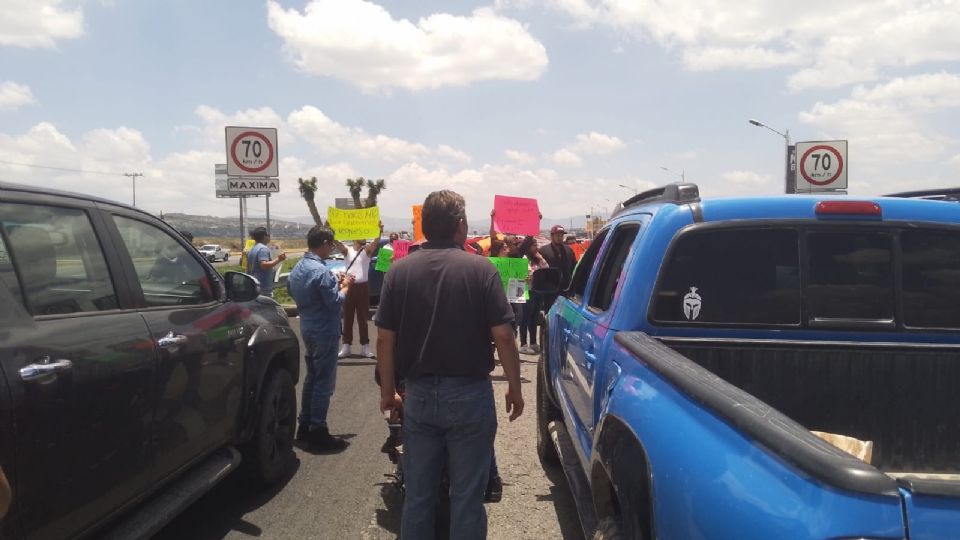 Hay al menos una docena de personas realizando el bloqueo, quienes portan pancartas